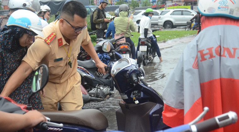 CSGT tổ chức dùng xe chuyên dụng đưa phương tiện của người dân thoát khỏi vùng ngập nước.