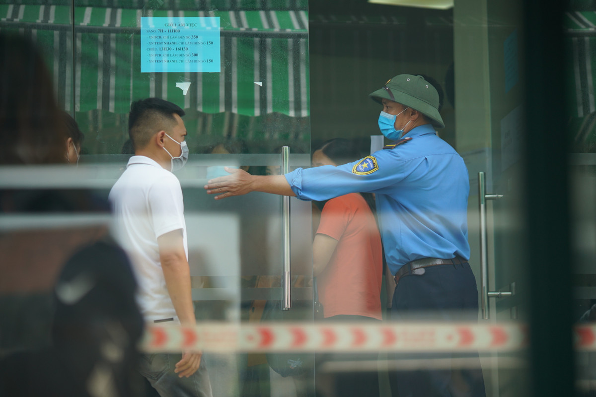 Nhân viên trung tâm xét nghiệm đã rất vất vả hướng dẫn người dân đứng giãn cách trong khi xếp hàng.