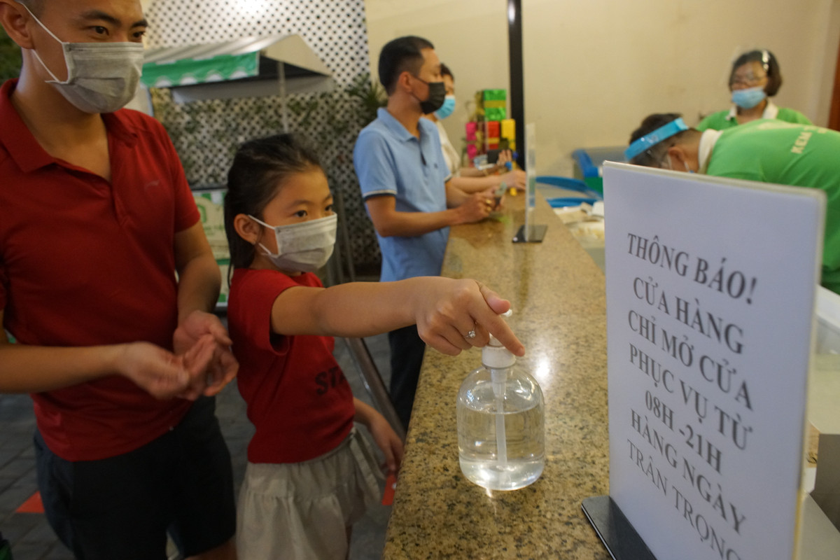 Khách vào mua kem ngoài xếp hàng còn phải khử khuẩn trước khi giao dịch với nhân viên bán hàng.