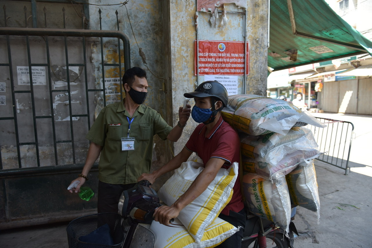 Trước khi vào chợ, người dân phải đo thân nhiệt, khử khuẩn tay trước sự giám sát của Ban Quản lý chợ.