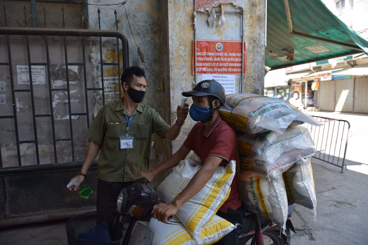 Trước khi vào chợ, người dân phải đo thân nhiệt, khử khuẩn tay trước sự giám sát của Ban Quản lý chợ.