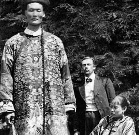 Đây là một người khổng lồ thời mạt Thanh, anh ta mặc trên người bộ quan phục của Đại Thanh, chiều cao vượt qua cả Diêu Minh thời nay! Người ngồi bên cạnh là vợ anh ta, về sau người vợ qua đời vì bệnh tật, anh ta tái hôn với một người vợ phương Tây. Anh ta đi lưu diễn ở Âu Mỹ, còn nhập quốc tịch Anh, cuối cùng chết ở nơi đất khách quê người!