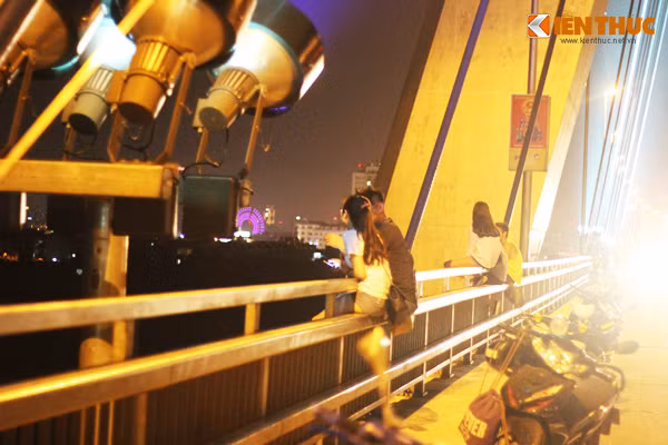 Nhiều cặp "uyên ương" chọn cầu Nhật Tân làm nơi hẹn hò, hóng gió. Tuy nhiên, bên cạnh việc dựng xe máy trên cầu vi phạm luật giao thông, các cặp đôi còn đua nhau ngồi vắt vẻo trên thành cầu bất chấp nguy hiểm.