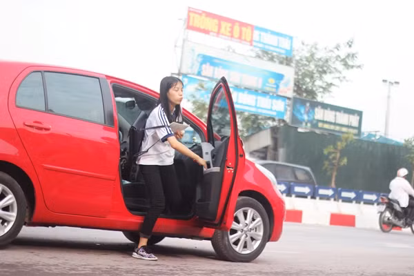 Nữ sinh vừa bước xuống ô tô vừa ôn bài.