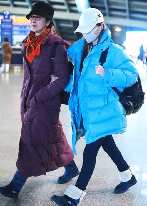 Lý Tiểu Lộ bịt khẩu trang kín mít và khoác chặt tay mẹ. Ảnh: Ifeng