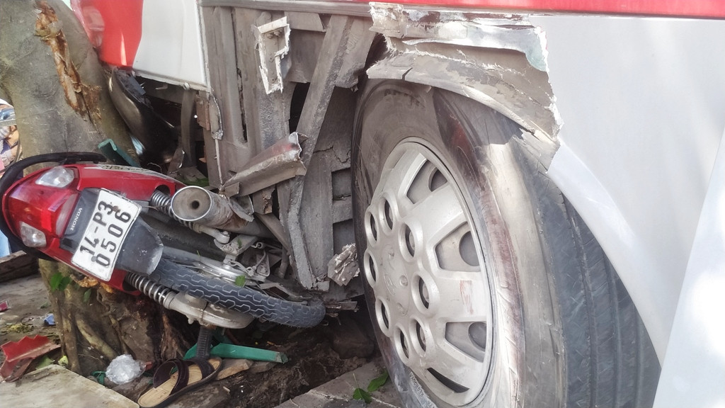 Một chiếc xe máy nằm bẹp dúm dưới đầu xe khách.