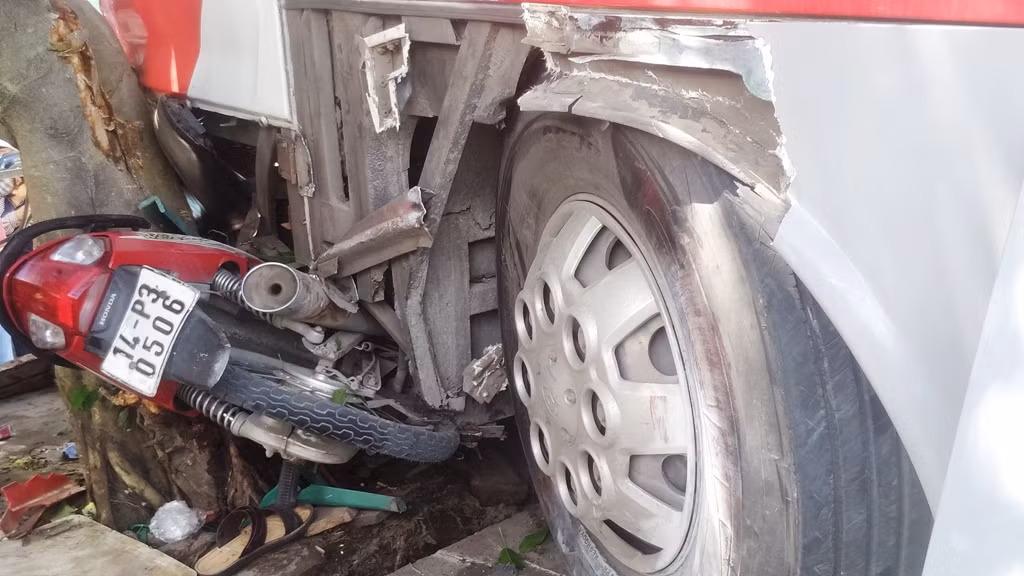 Một chiếc xe máy nằm bẹp dúm dưới đầu xe khách.