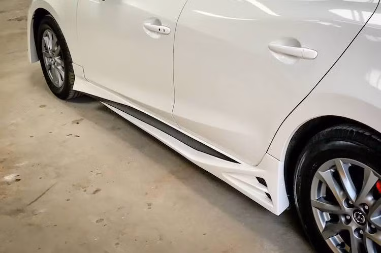 Dọc theo trục cơ sở của Mazda 3, Phi Long cũng đã trang bị cho chiếc xe những nẹp hông phong cách thể thao với thiết kế góc cạnh. Bộ mâm nguyên bản trên xe đang tạm thời được chủ nhân giữ nguyên. Tuy nhiên ở phía sau bộ mâm, các heo phanh đã được lắp ốp phong cách Brembo với màu đỏ nổi bật.