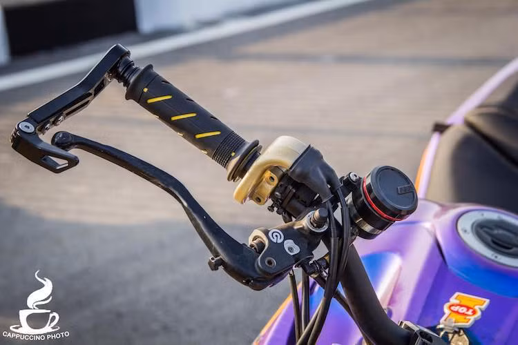 Nằm ở hai bên ghi-đông cũng là một số món "đồ chơi" khác nhau như bình dầu AEM titan, cùm ga Domino, bao tay Domino, cùm phanh Brembo, cùm côn Accossato và gương hậu gắn gù CRG.