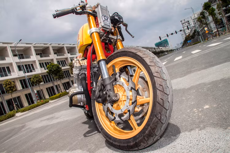Vốn được trang bị cặp phuộc ống lồng nguyên bản, tuy nhiên chiếc CB750 cafe racer phiên bản mới nay đã sở hữu phuộc USD với đường kính lớn từ một mẫu xe phân khối lớn khác. Trên bản độ này, Tự Thanh Đa đã giữ mâm 6 cánh của CB750, nhưng nâng cấp hệ thống phanh với đĩa mới cùng heo Tokico 4 piston bắt dọc..