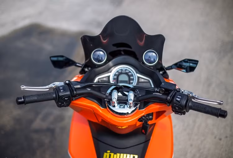 Ghi-đông nguyên bản của của chiếc xe tay ga PCX vốn khá cao do hướng tới sự thoải mái, chính vì vậy để tạo phong cách thể thao hơn, chủ xe đã thay ghi-đông thấp hơn của Jet's 2 Wheels. Nằm 2 bên tay lái là cặp bao tay từ hãng Kitaco (Nhật Bản) và tay phanh của CRG.