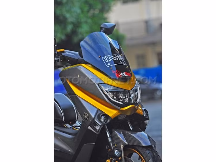 Ở phía trước, chóa đèn pha cùng các đèn demi của N-Max đã được anh Widia thay thế hoàn toàn sang các bóng cầu dạng thấu kính projector được lấy từ xe hơi Mazda MX-5. Nằm ở phía bên dưới đèn pha, chắn bùn trước của chiếc xe đã được làm từ sợi carbon siêu nhẹ và còn có thêm một đèn LED Cree ở bên phuộc phải.