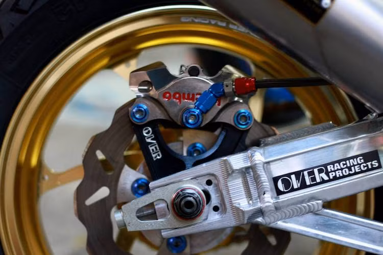 Ở phía sau, bộ gắp nhôm hàn chắc chắn của Over Racing, pát heo Over, heo Brembo và đĩa Galfer cũng đã thay thế cho các chi tiết nguyên bản của MSX.