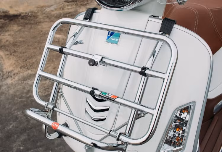 Nằm ở bên dưới yếm trước của xe là giá để đồ bằng inox do hãng Faco của Ý sản xuất để Piaggio sử dụng làm phụ kiện chính hãng. Với một đầu treo trên yếm và đầu còn lại sử dụng giác hút gắn với thân xe, giá để đồ này có lò xo để tự gấp gọn khi cần thiết và chịu được tải trọng khoảng 5kg.