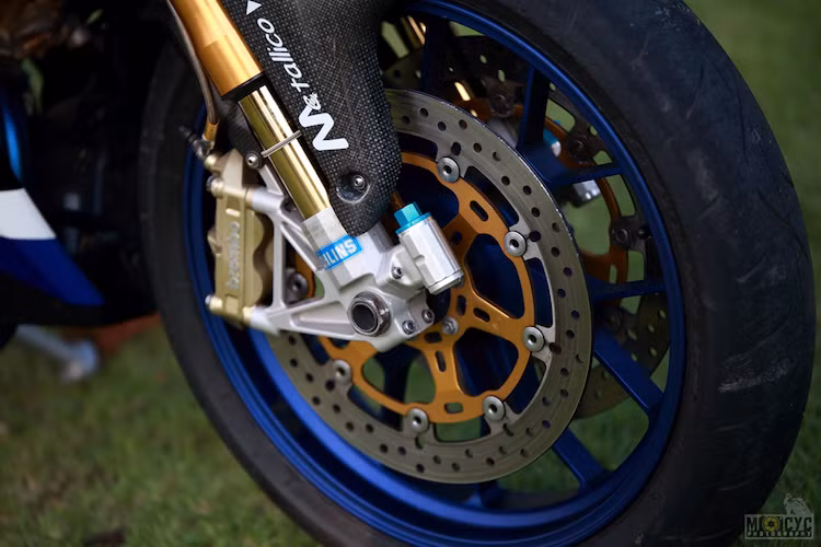 Để có thể lắp được vào Exciter, cặp phuộc Ohlins của RSV4 đã buộc phải được cắt ngắn từ lò xo tới vỏ phuộc, sau đó tiếp tục lắp vào chảng 3 đặc chế để phù hợp với cổ của xe. Đây là công đoạn phức tạp nhất, đòi hỏi độ chính xác cực cao khi cắt phuộc.