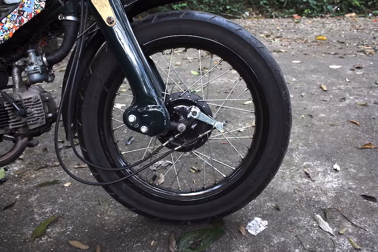 Ở phía trước, chiếc xe máy số Honda Super Cub đời cũ đã được độ bánh lớn bằng cách nâng bản vành lên thành 2.5/17, đi kèm với lốp 100/80/17. Hệ thống phanh đùm phía trước cùng với phuộc "giò gà" đặc trưng của Super Cub đã được chủ xe giữ lại.
