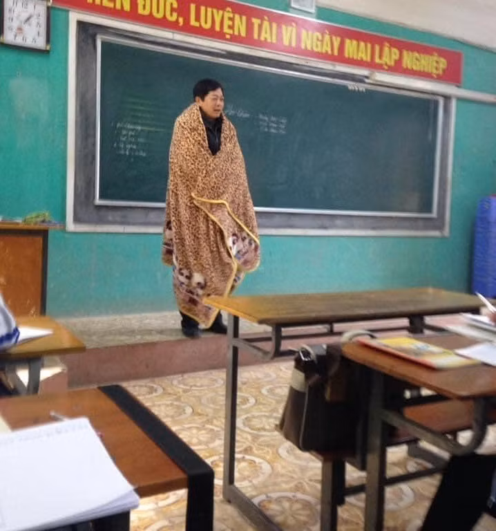 Theo đó, bức ảnh gây chú ý về thầy giáo đang đứng trên bục giảng nhưng trên người thầy lại khoác tấm chăn lớn phủ kín từ vai đến chân. Một số dân mạng cho rằng, trong điều kiện thời tiết miền Bắc rét buốt như hiện tại, không chỉ có các cô cậu học trò mà đến thầy cô cũng phải "đầu hàng" trước thời tiết này. Ảnh: Tin Bắc Giang