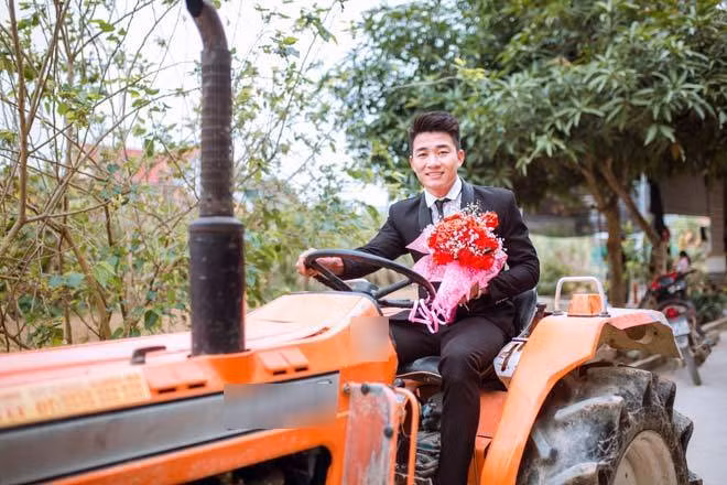 Cặp đôi cô dâu – chú rể cùng ngồi trên chiếc máy cày "hầm hố”, theo sau là dàn quan khách hồ hởi đưa dâu. Chú rể không giấu nổi được sự phấn khích khi được lái máy cày đến đón vợ mình. Ảnh: FBNV