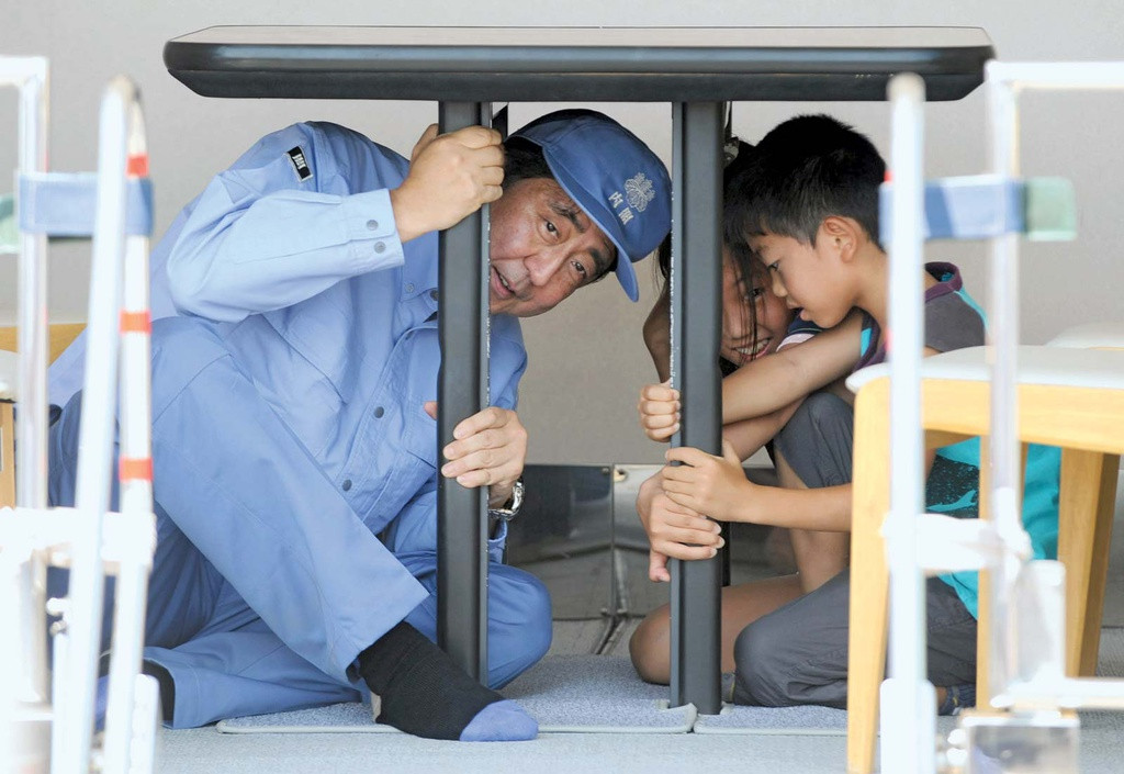 Theo Wall Street Journal, ông Abe được đánh giá là người đã định hình lại nước Nhật thời hiện đại, bao gồm phục hưng nền kinh tế Nhật từ tình trạng trì trệ những năm 1990. Kế hoạch phục hưng nền kinh tế Nhật Bản của ông, có tên là Abenomics, thúc đẩy thị trường chứng khoán phục hồi và tăng lợi nhuận doanh nghiệp. Trong ảnh, ông Abe cùng các học sinh ở thành phố Chiba tham gia cuộc diễn tập thảm họa toàn quốc ngày 1/9/2013. Ảnh: AP.