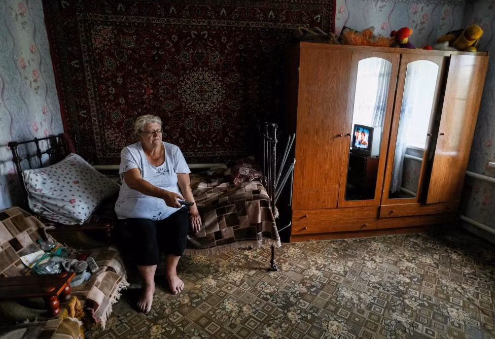Bà Lena Ivanova đang theo dõi truyền hình trong căn nhà ngoài chiến tuyến gần Avdeyevka. Nằm cách thành trì phe ly khai là Donetsk chỉ chừng 9 dặm, Avdeyevka là tâm cuộc xung đột ở miền đông Ukraine đã cướp đi sinh mạng của hơn 9.500 người kể từ đầu năm 2014.