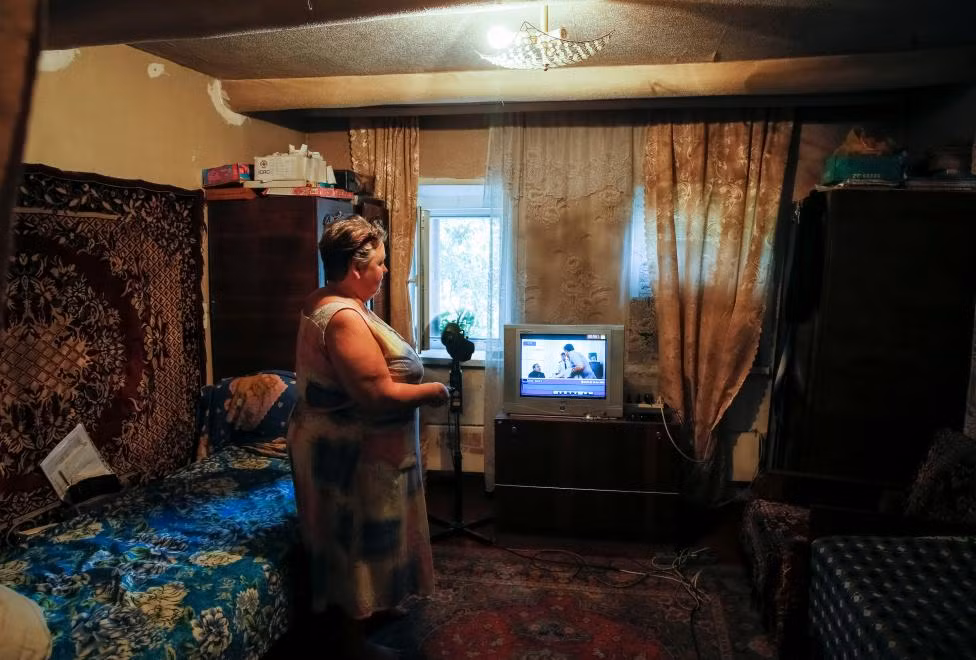 Bà Olha Shazhkova chỉ cho phóng viên xem một trong những kênh truyền hình do lực lượng ly khai thân Nga chiếu trên chiếc ti vi ở căn nhà bà thuộc thị trấn Avdeyevka.