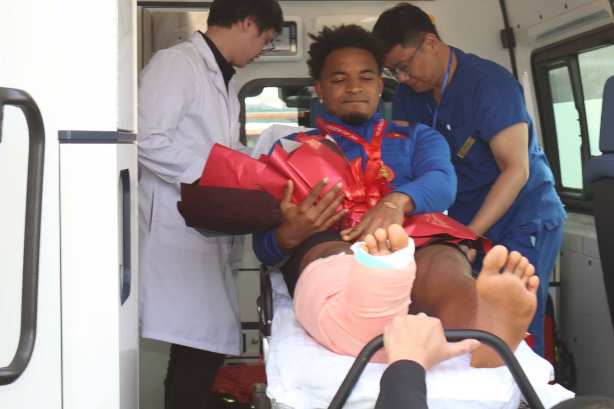 Trong vòng vây của người hâm mộ, cầu thủ nén đau, mỉm cười cảm nhận niềm vui chiến thắng tại Việt Nam.