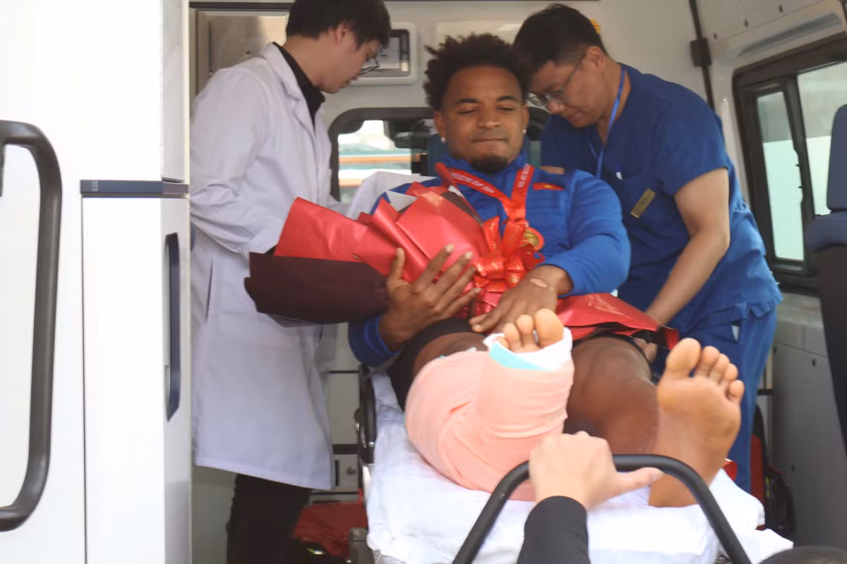 Trong vòng vây của người hâm mộ, cầu thủ nén đau, mỉm cười cảm nhận niềm vui chiến thắng tại Việt Nam.