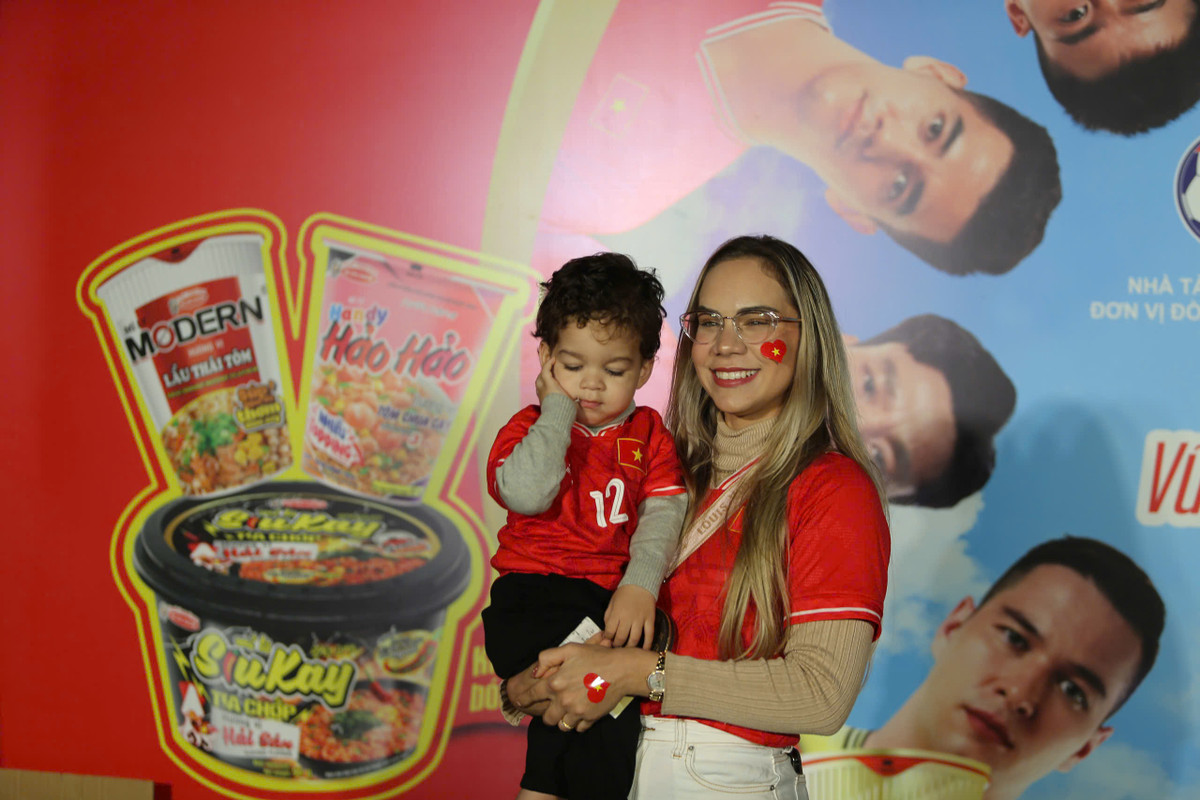 Vợ Xuân Son xuất hiện rạng rỡ. Cô mặc áo đỏ của đội tuyển và dán lá cờ tổ quốc.