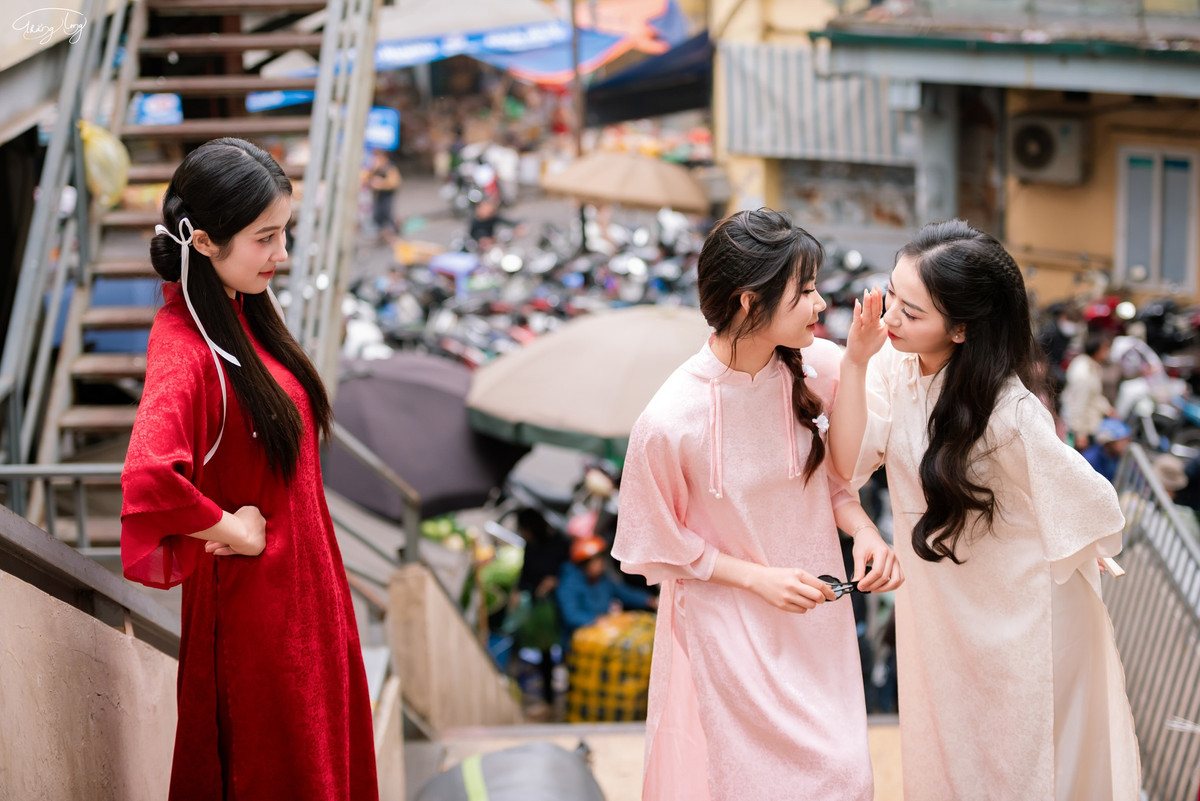 Những nhóm bạn gái diện áo dài truyền thống, tay trong tay bước trên cầu thang mang nét cổ kính đặc trưng của chợ. Áo dài đỏ thắm, áo dài hồng đào, áo dài trắng tinh khôi... mỗi người một vẻ, nhưng đều toát lên vẻ đẹp dịu dàng, duyên dáng của người con gái Việt.
