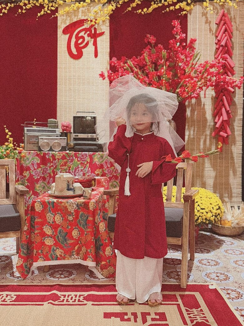 Nhóc tỳ đã được bố mẹ cho lên đồ để chụp bộ ảnh Tết vô cùng rực rỡ. Cô bé diện áo dài đỏ, mang guốc mộc trông vô cùng đáng yêu.