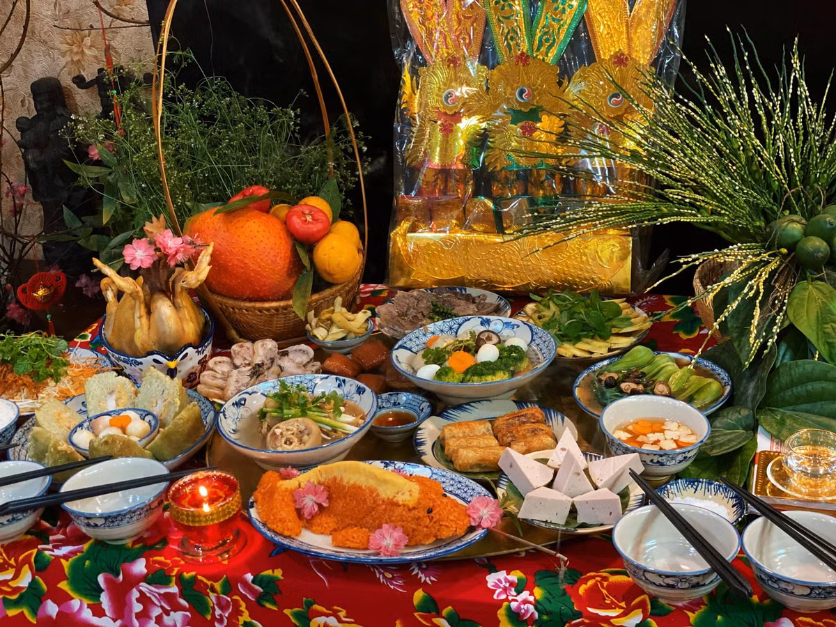 Mâm cỗ cúng gồm các món gà luộc, bánh chưng, nộm bò khô, cá lăng nướng, giò lụa, xôi gấc, canh măng, canh miến, bánh bao kim tiền, cơm trắng, hoa quả.