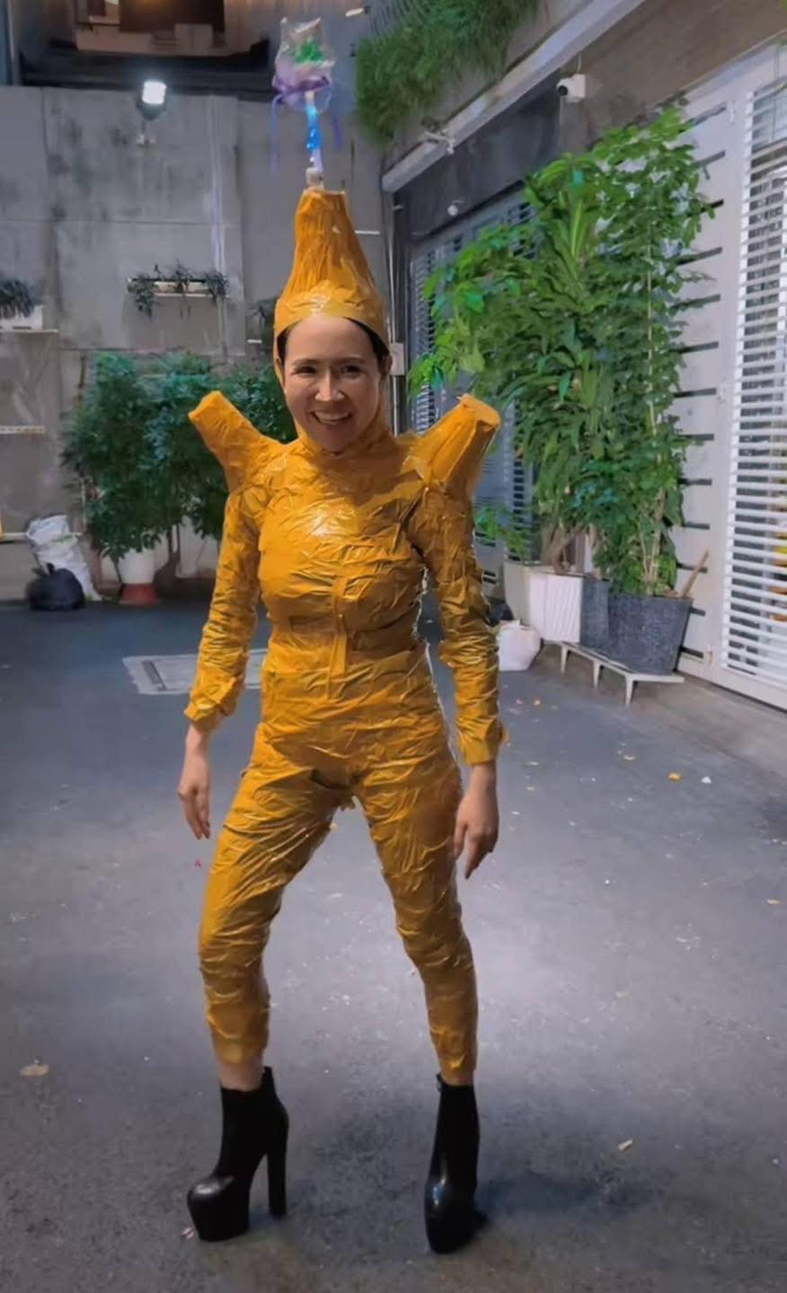 Mặc kệ cả cộng đồng Tiktok quấn băng keo để khoe dáng, "bà trùm nông sản" đu trend theo một phong cách độc lạ, riêng biệt. Theo đó, cô nàng cũng có quấn băng keo để làm trang phục, tuy nhiên bộ trang phục này được quấn kít mít từ thân xuống chân. Đặc biệt, cô nàng còn gắn thêm chiếc đèn phía sau để cosplay thành...đom đóm.