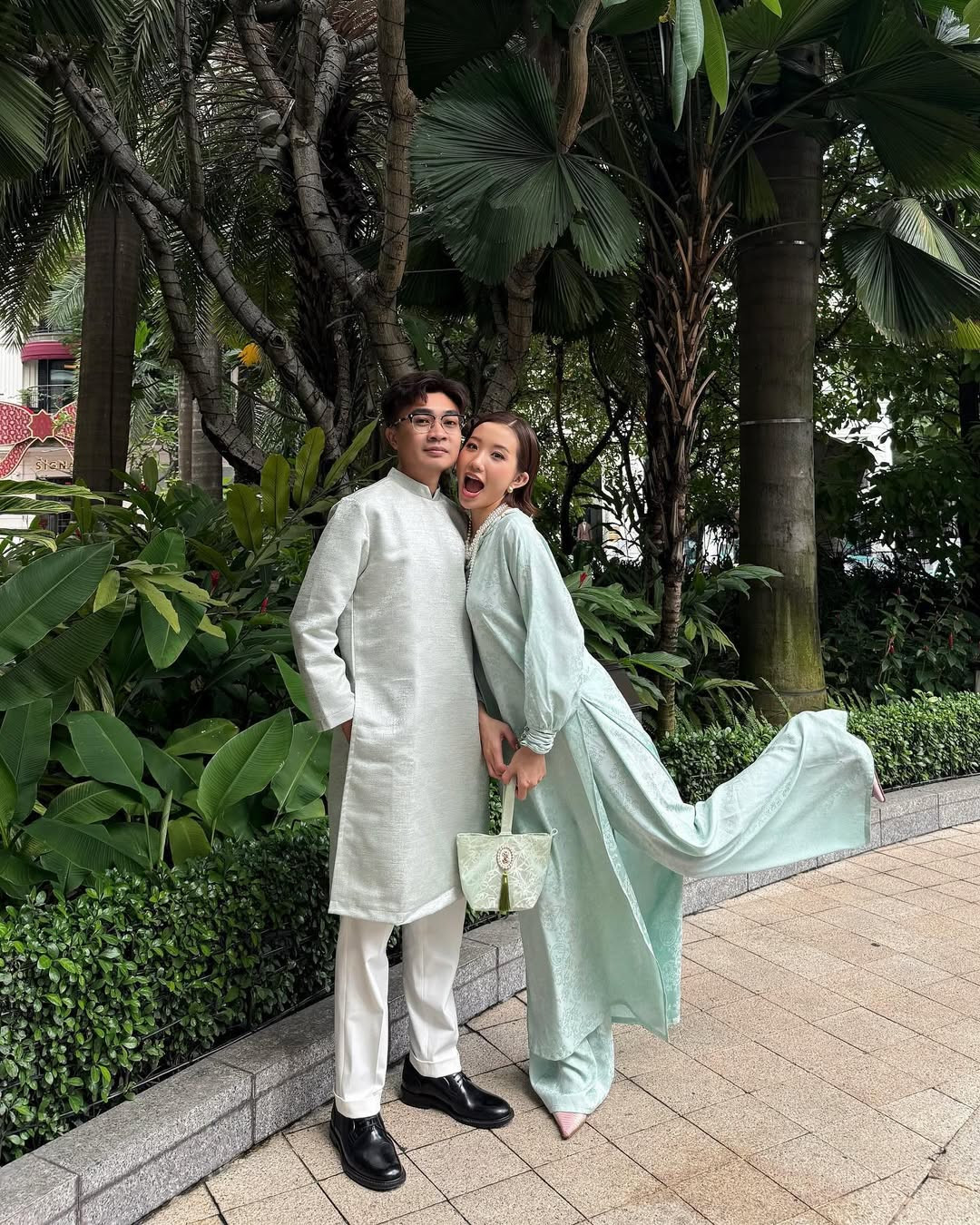 Không lựa chọn trang phục quá cầu kỳ, Huyền 2k4 diện thiết kế áo dài với phom suông màu xanh mint pastel nhẹ nhàng, kết hợp cùng một chiếc túi tone sur tone, còn Duy Nhỏ cũng diện chiếc áo dài màu đồng bộ với bà xã.