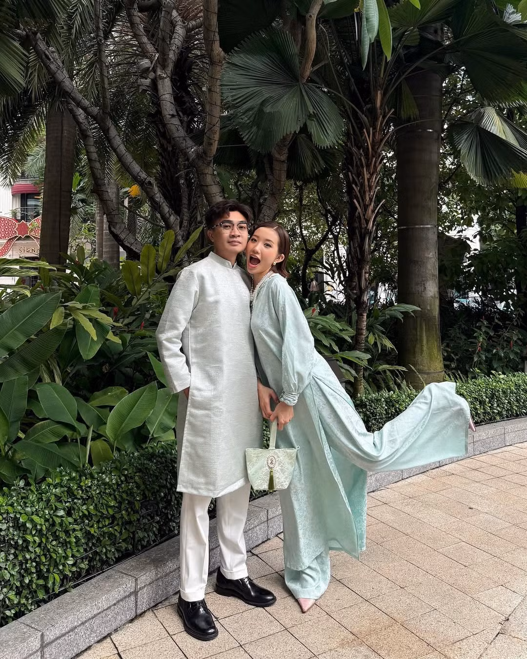 Không lựa chọn trang phục quá cầu kỳ, Huyền 2k4 diện thiết kế áo dài với phom suông màu xanh mint pastel nhẹ nhàng, kết hợp cùng một chiếc túi tone sur tone, còn Duy Nhỏ cũng diện chiếc áo dài màu đồng bộ với bà xã.