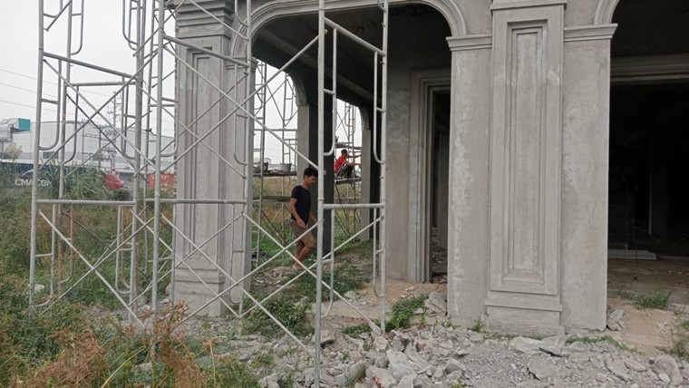 Các công nhân leo giàn giáo làm việc ngay sát đường điện cao thế.