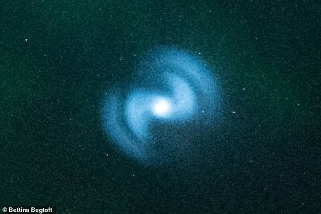 Vật thể này có hình dáng giống UFO, trông như một vòng xoắn ốc màu xanh đầy bí ẩn. Quan sát bằng mắt thường, nó có màu trắng, nhưng khi chụp bằng máy ảnh Nikon D750 thì lại có màu xanh tuyệt đẹp, tạo ra hình ảnh giống như một tàu vũ trụ của người ngoài hành tinh hoặc một thiên hà mới xuất hiện trên bầu trời.