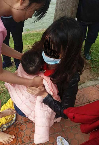 Cháu bé được trùm khăn, bàn giao lại cho người mẹ.