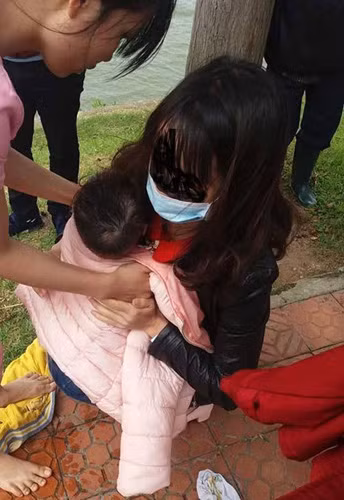 Cháu bé được trùm khăn, bàn giao lại cho người mẹ.