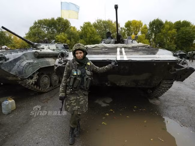 Dịu dàng khoác súng tạo dáng bên... xe thiết giáp. Nguồn ảnh: Sina.