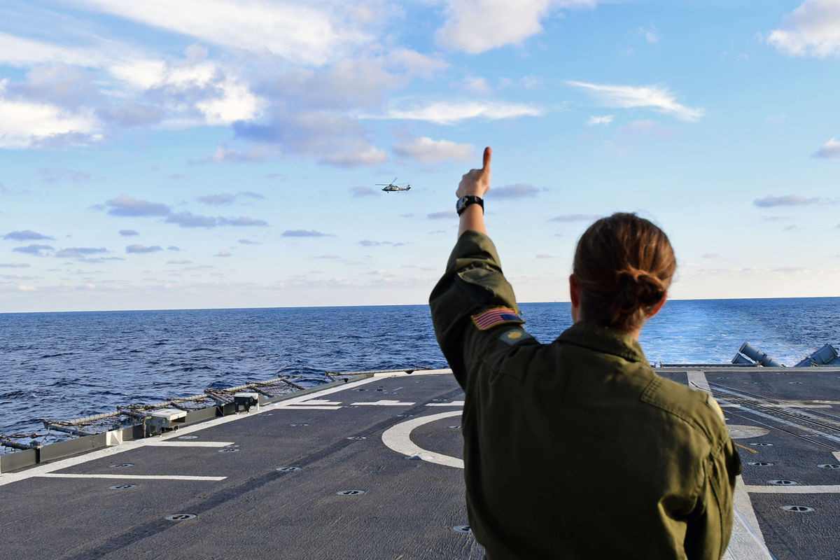 Một nữ sĩ quan không quân đang vẫy chào người đồng nghiệp của mình trên chiếc MH-60R Seahawk từ sân đỗ trực thăng trên chiếc USS Hue City. Nguồn ảnh: Militarynews.