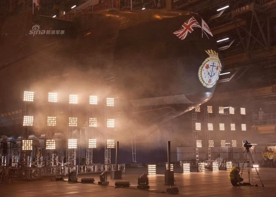 Buổi lễ có sự tham gia của Đô đốc Hải quân Hoàng gia Anh ông Philip Jones cùng vợ mình bà Elizabeth Jones, theo đúng nghi thức truyền thống, vợ của đô đốc hải quân đã đập chai rượu vào thành tàu chính thức "khai trương" chiếc tàu ngầm hạt nhân này. Nguồn ảnh: Sina.