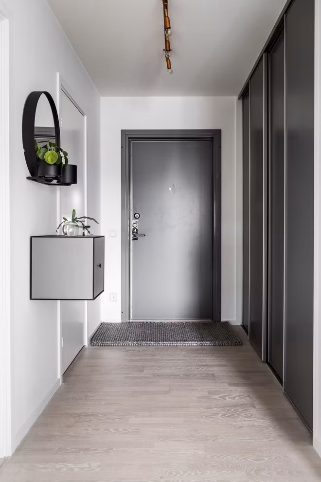 Không cần quá cầu kỳ trong việc trang trí hay thêm pha nhiều màu sắc, căn hộ nhỏ của anh chàng độc thân này đã khiến nhiều người phải ghen tỵ khi sử dụng màu trắng kết hợp ăn ý, hài hòa với màu xám, tạo nên vẻ đẹp hiện đại và thanh lịch xuyên suốt các khu vực chức năng. Ảnh: Lối vào nhà giản dị với hệ thống tủ âm tường, cửa trượt của tủ được chọn lựa màu xám giúp không gian trở nên bình dị và ấm áp hơn.