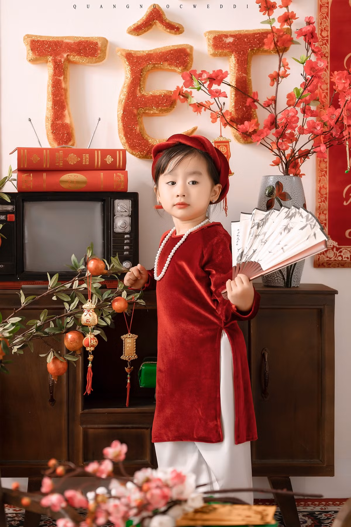 Bộ ảnh Tết của bé Sữa mang hơi hướng cổ xưa với không gian ấm cúng của những chiếc tủ gỗ, bàn ghế gỗ, ti vi đen trắng, bánh chưng, hoa đào...