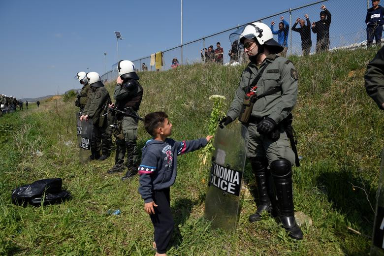 Một bé trai bất ngờ tặng hoa cho cảnh sát chống bạo động Hy Lạp gần khu trại Diavata.