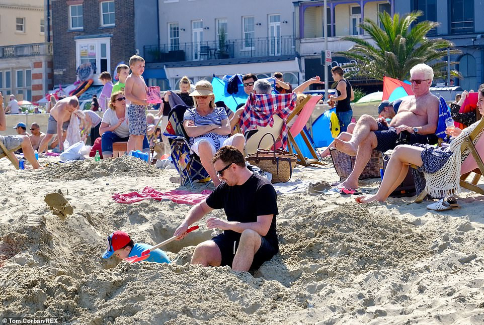 Một bé trai đùa nghịch ở bãi cát trên bãi biển Weymouth.