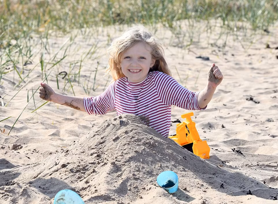 Bé gái chơi đùa ở bãi biển Berwick, Northumberland.