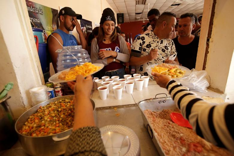 Các di dân Cuba nhận đồ ăn tại một nhà thờ được sử dụng làm nơi trú ẩn tạm thời ở Ciudada Juarez ngày 6/4.