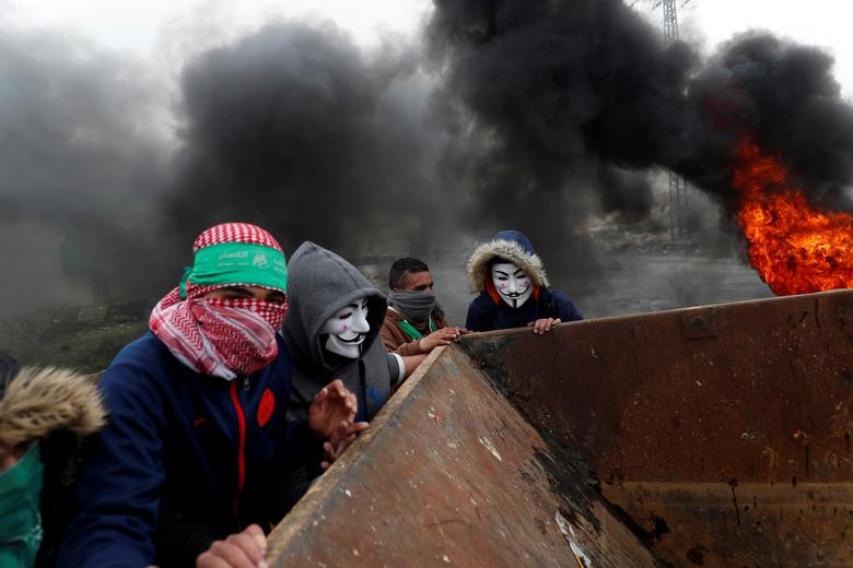Những người biểu tình Palestine đeo mặt nạ dựng hàng rào trong cuộc đụng độ với lực lượng Israel gần khu định cư Do Thái Beit El ở Bờ Tây ngày 30/3.