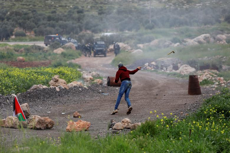 Một người biểu tình Palestine ném đá về phía các binh sĩ Israel tại làng al-Mughayer cuối tuần qua.