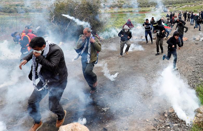Những người biểu tình Palestine chạy qua làn hơi cay mù mịt ở làng al-Mughayer, Bờ Tây, ngày 29/3.
